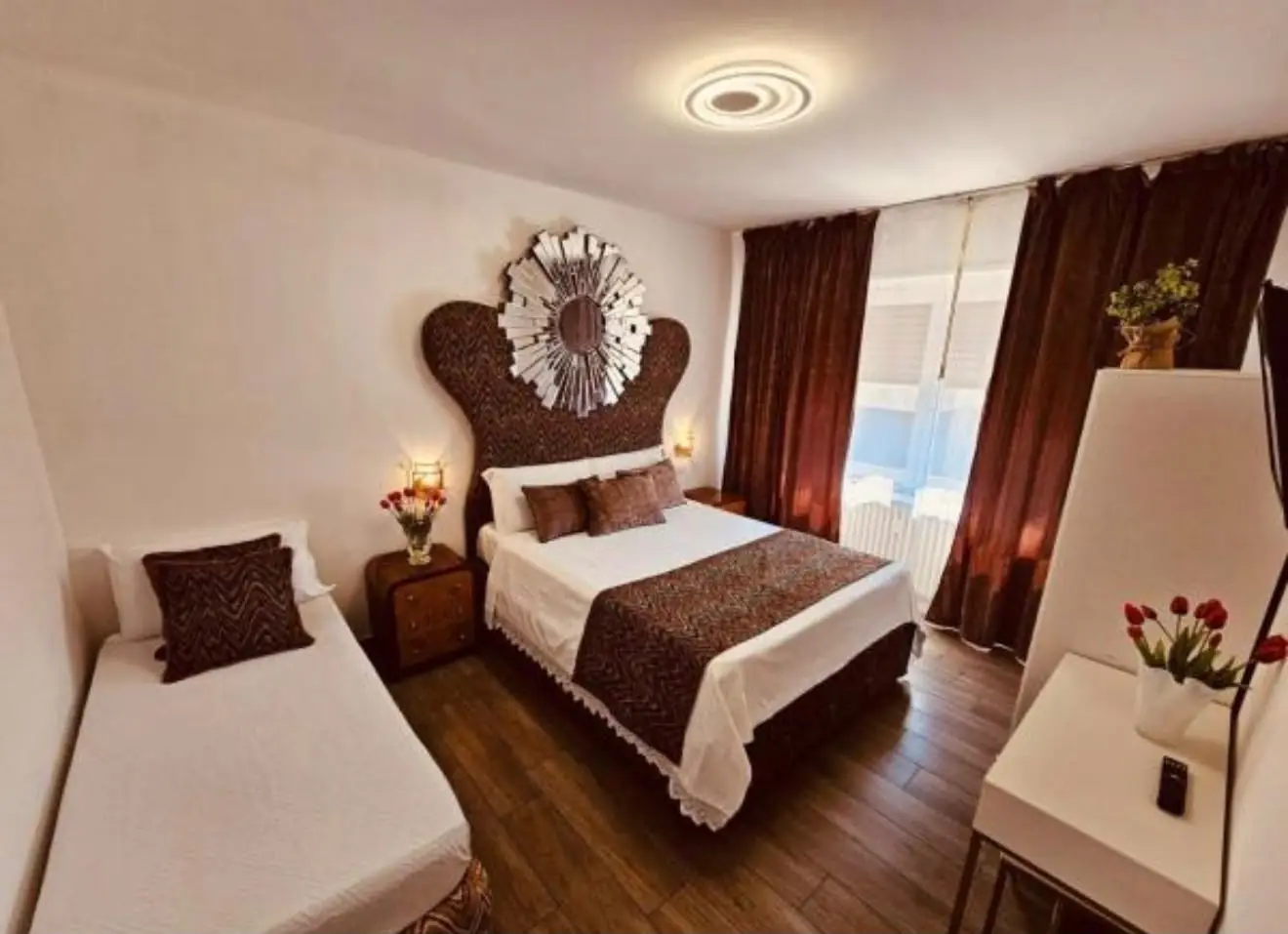 Family Suite — queen and single bed beneath a sunburst mirror